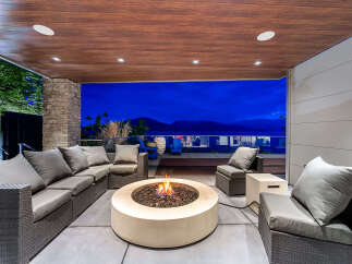Experience luxurious outdoor living with this stunning patio featuring a modern sectional sofa and a captivating fire pit.