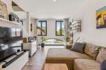 Experience modern living in this stylish apartment featuring a spacious open-plan living area with a large sectional sofa and entertainment center.