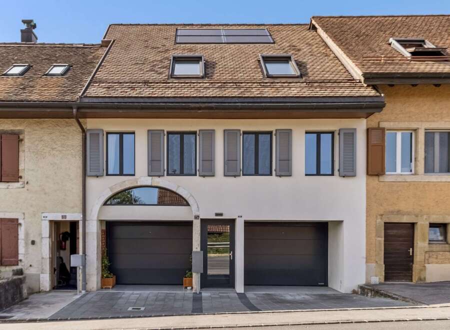 Discover this charming property featuring a modern facade with two spacious garage doors and a central entrance.
