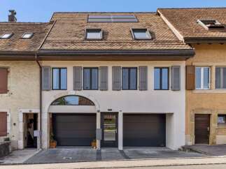 Discover this charming property featuring a modern facade with two spacious garage doors and a central entrance.