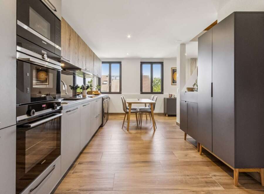Discover this modern kitchen featuring sleek grey cabinetry and integrated Siemens appliances, including a microwave and oven.