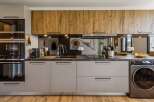 This modern kitchen boasts sleek, light gray cabinetry complemented by warm, wood-grain upper cabinets.