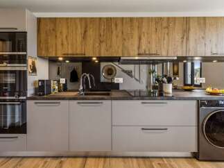 This modern kitchen boasts sleek, light gray cabinetry complemented by warm, wood-grain upper cabinets.