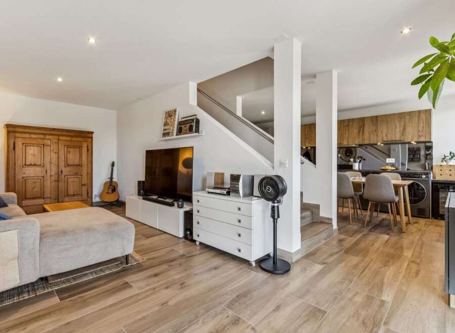 Discover this modern living space featuring a comfortable sectional sofa, a large flat-screen TV, and a stylish wooden cabinet.
