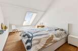 Discover this charming attic bedroom featuring a comfortable bed with a unique patterned duvet.