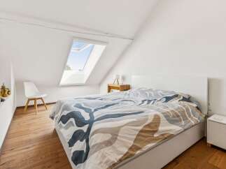 Discover this charming attic bedroom featuring a comfortable bed with a unique patterned duvet.