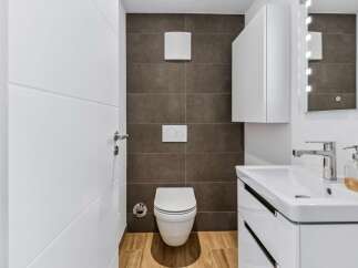This modern bathroom features a sleek white toilet with a concealed cistern and a stylish white vanity with a vessel sink.