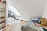 This charming attic bedroom features a cozy bed adorned with playful stuffed animals and a unique patterned duvet.