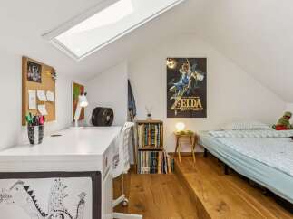 This attic bedroom offers a unique and functional living space, perfect for a child or young adult.