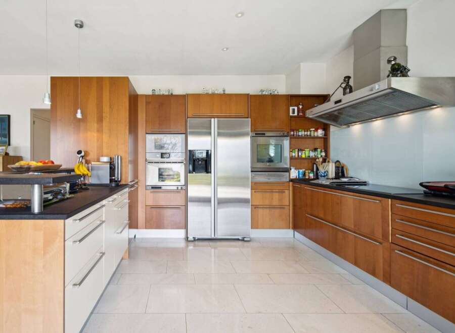 This modern kitchen boasts sleek, custom wood cabinetry and a spacious stainless steel refrigerator.