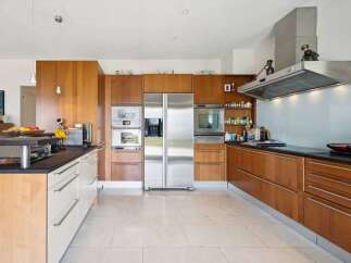 This modern kitchen boasts sleek, custom wood cabinetry and a spacious stainless steel refrigerator.