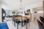 Experience modern living in this spacious open-plan home, featuring a stylish dining area with a round wooden table and black chairs, perfect for family gatherings.