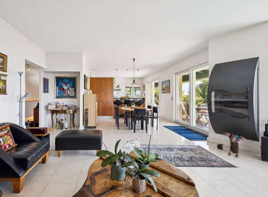 Experience modern living in this spacious open-concept home, featuring a sleek black leather sofa and ottoman perfect for relaxation.