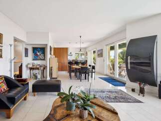 Experience modern living in this spacious open-concept home, featuring a sleek black leather sofa and ottoman perfect for relaxation.