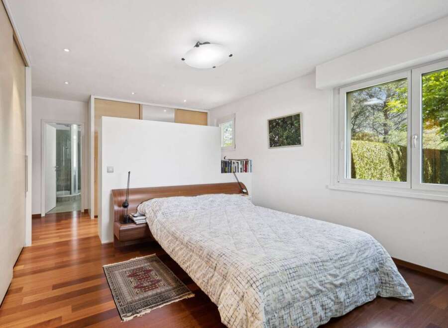 Experience serene living in this beautifully appointed bedroom, featuring a comfortable bed with a patterned duvet and a rich wooden headboard.