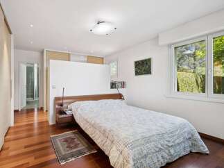 Experience serene living in this beautifully appointed bedroom, featuring a comfortable bed with a patterned duvet and a rich wooden headboard.