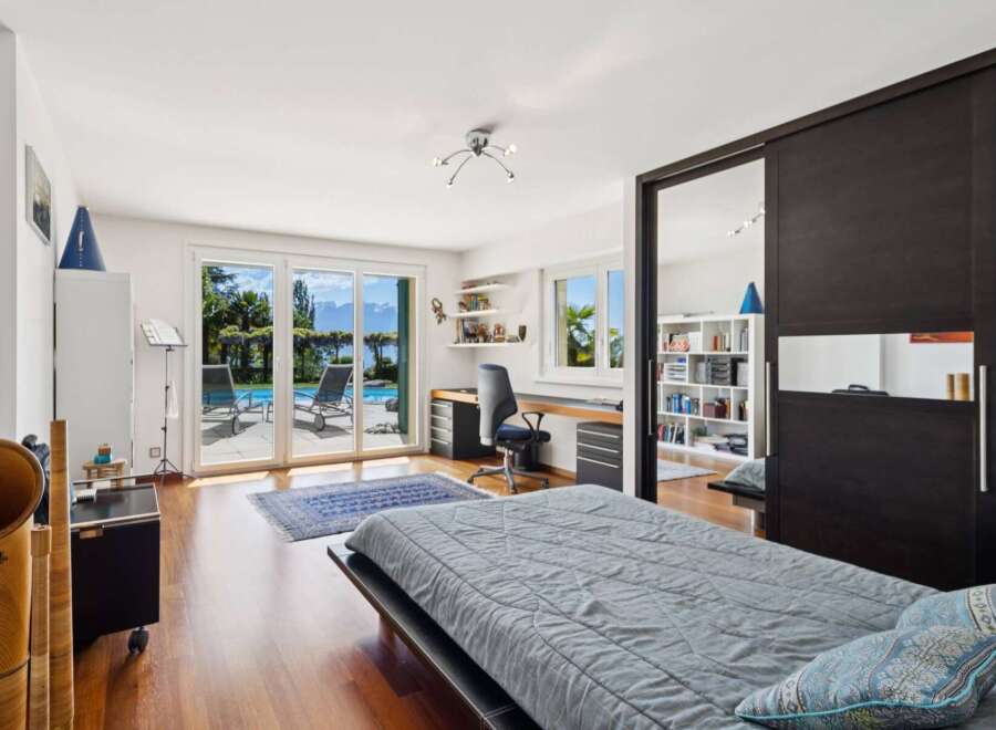 This spacious bedroom offers a serene retreat with stunning views of a private pool and a picturesque lake.
