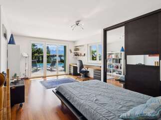 This spacious bedroom offers a serene retreat with stunning views of a private pool and a picturesque lake.