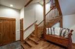 This charming entryway features a rustic wooden staircase with a matching bench adorned with plush pillows, creating a warm and inviting atmosphere.