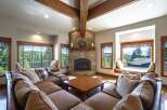 Experience breathtaking mountain views from this stunning living room, featuring a grand stone fireplace and expansive windows.