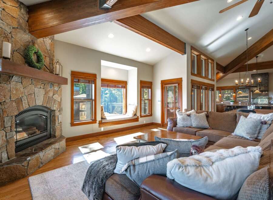 Experience rustic charm in this spacious living room, featuring a grand stone fireplace and exposed wooden beams that add warmth and character.