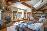 Experience rustic charm in this spacious living room, featuring a grand stone fireplace and exposed wooden beams that add warmth and character.