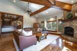 Experience rustic elegance in this spacious living room, featuring a grand stone fireplace and exposed wooden beams that create a warm, inviting atmosphere.
