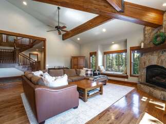 Experience rustic elegance in this spacious living room, featuring a grand stone fireplace and exposed wooden beams that create a warm, inviting atmosphere.