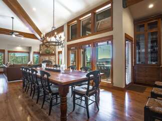 Experience luxurious mountain living in this stunning dining room, featuring a grand wooden table perfect for hosting.