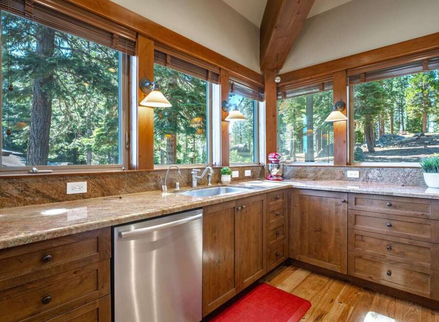 Experience breathtaking forest views from this stunning kitchen, featuring granite countertops and custom wood cabinetry.