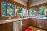 Experience breathtaking forest views from this stunning kitchen, featuring granite countertops and custom wood cabinetry.