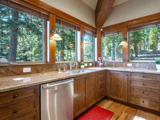 Experience breathtaking forest views from this stunning kitchen, featuring granite countertops and custom wood cabinetry.