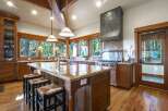 Experience luxury mountain living in this stunning kitchen, featuring a large granite island with bar seating and a professional-grade gas range with a custom hood.