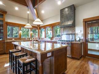 Experience luxury mountain living in this stunning kitchen, featuring a large granite island with bar seating and a professional-grade gas range with a custom hood.