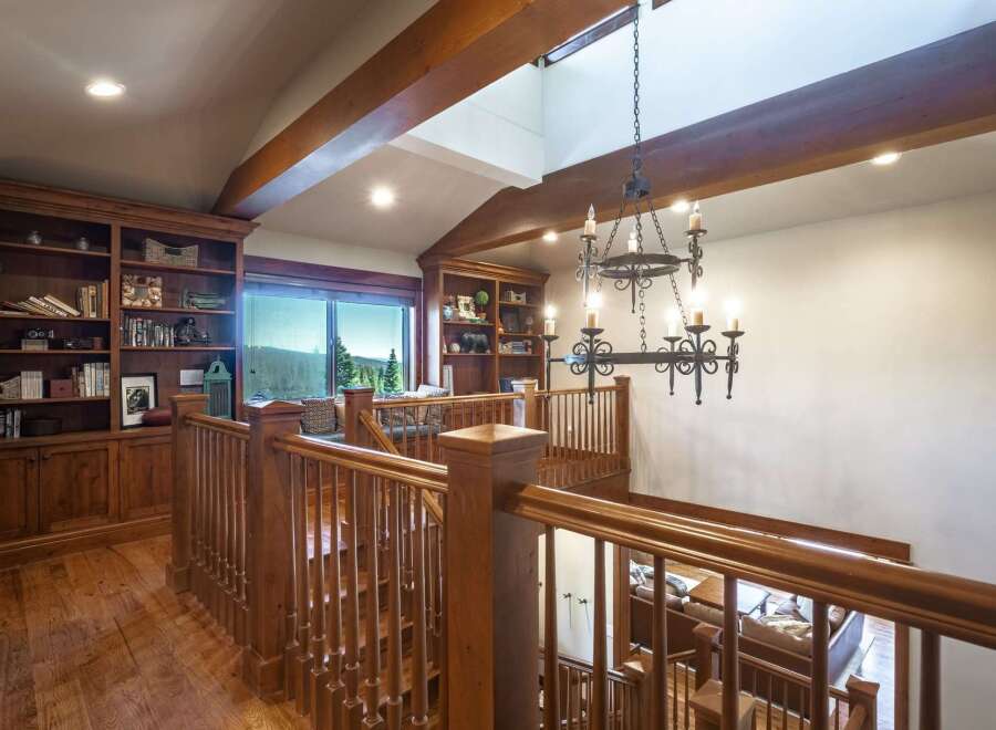Experience rustic elegance in this stunning home featuring a grand wooden staircase and a dramatic chandelier.