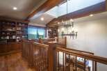 Experience rustic elegance in this stunning home featuring a grand wooden staircase and a dramatic chandelier.