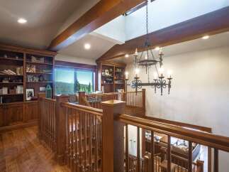 Experience rustic elegance in this stunning home featuring a grand wooden staircase and a dramatic chandelier.