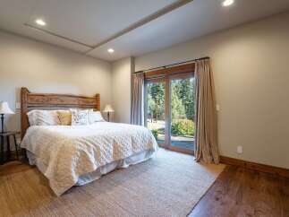 Experience serene mountain living in this charming bedroom, featuring a rustic wooden headboard and a plush white comforter.
