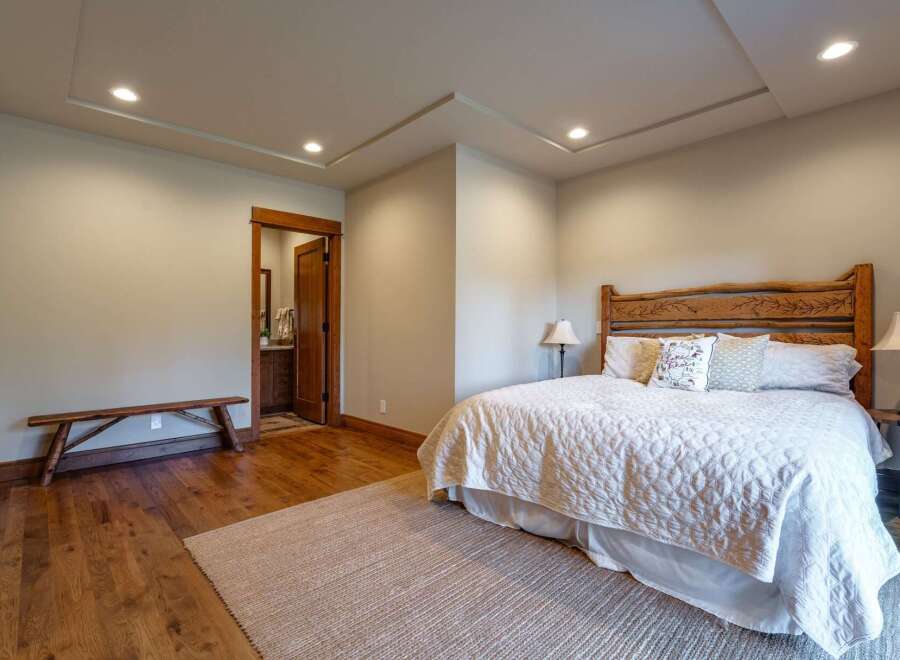 Experience rustic charm in this inviting bedroom featuring a unique log headboard and a cozy quilted bedspread.