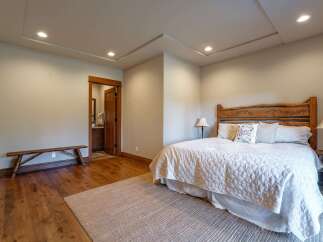 Experience rustic charm in this inviting bedroom featuring a unique log headboard and a cozy quilted bedspread.