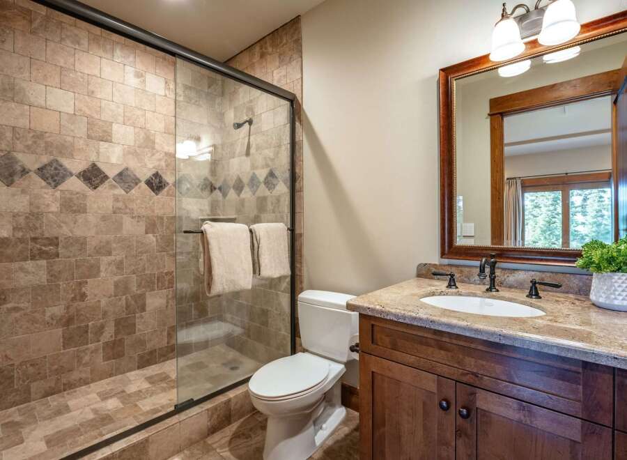 Experience luxury in this beautifully appointed bathroom, featuring a spacious walk-in shower with elegant tilework and a decorative accent band.