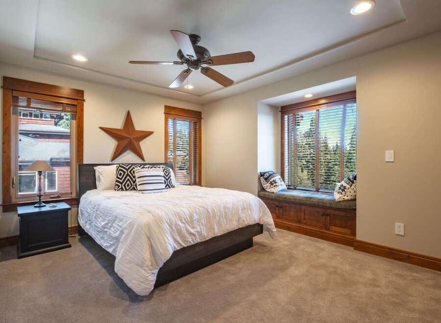 Experience rustic charm in this inviting bedroom, featuring a comfortable bed adorned with decorative pillows and a large wooden star accent.
