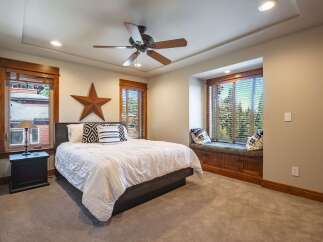 Experience rustic charm in this inviting bedroom, featuring a comfortable bed adorned with decorative pillows and a large wooden star accent.