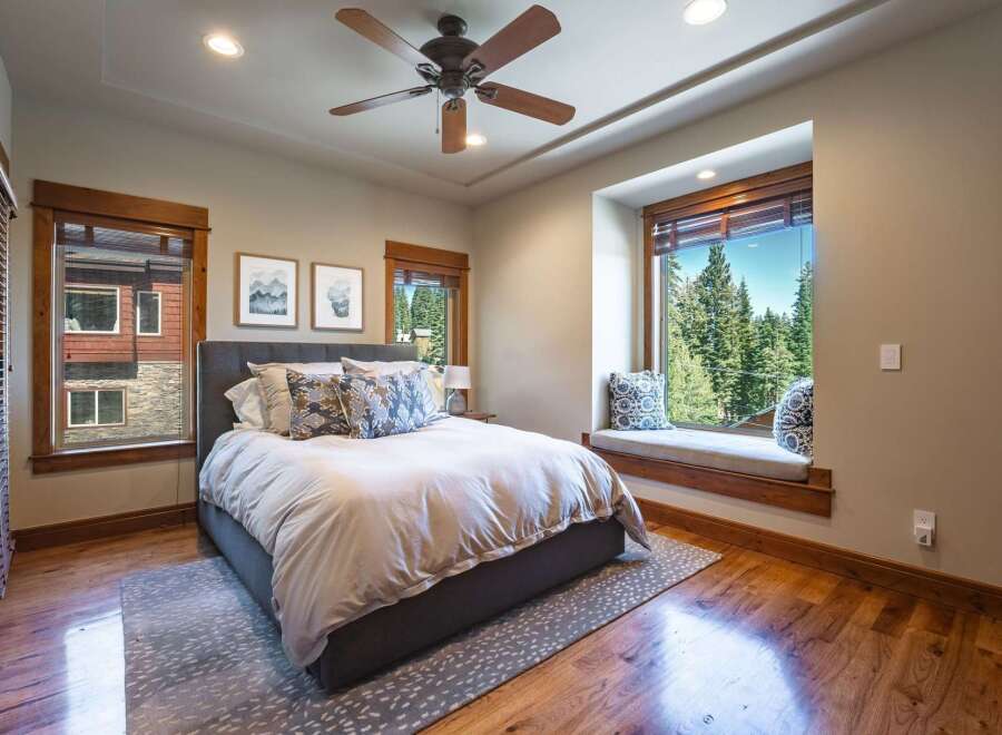 Experience ultimate relaxation in this serene bedroom, featuring a plush king-size bed adorned with decorative pillows and a cozy window seat offering breathtaking forest views.