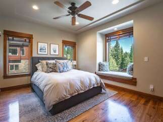 Experience ultimate relaxation in this serene bedroom, featuring a plush king-size bed adorned with decorative pillows and a cozy window seat offering breathtaking forest views.