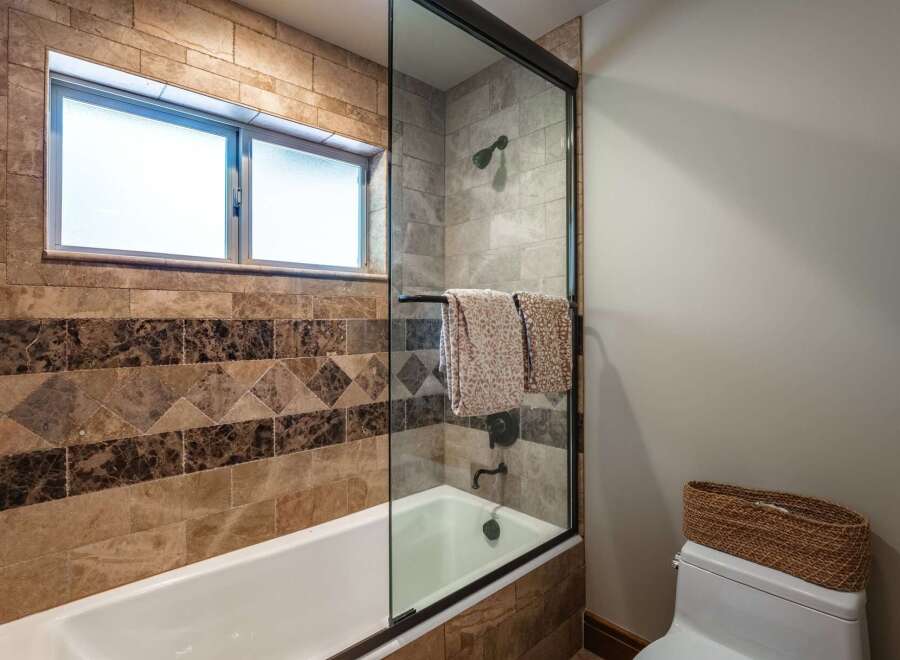 This luxurious bathroom features a deep soaking tub with a glass enclosure, perfect for unwinding after a long day.