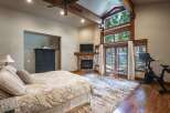 Experience ultimate comfort in this luxurious bedroom, featuring a cozy fireplace and a large window with stunning forest views.