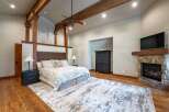 Experience rustic luxury in this master bedroom featuring exposed wooden beams and a stone fireplace.
