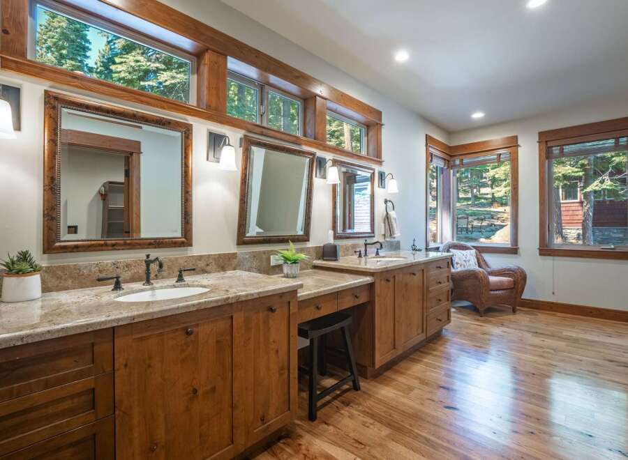 This spacious bathroom features dual vanities with granite countertops and ample wooden cabinetry, perfect for storage.