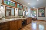 This spacious bathroom features dual vanities with granite countertops and ample wooden cabinetry, perfect for storage.